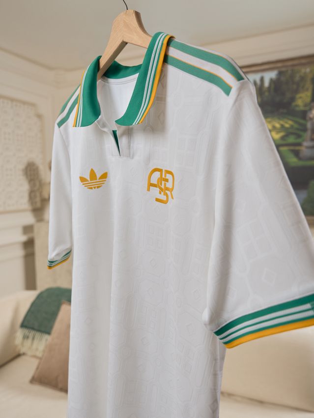 The white, Teal and Gold As Roma 3rd kit on a hanger in a fancy cream coloured room.